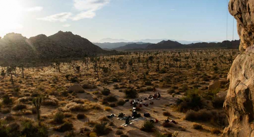 From above, a group of people appear small amidst a desert landscape. 